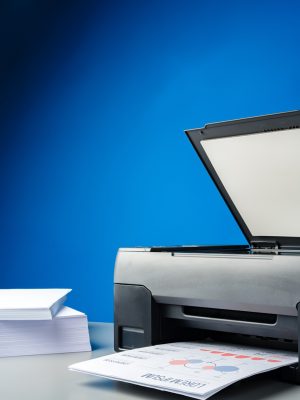 Laser printer on desk against blue background close up